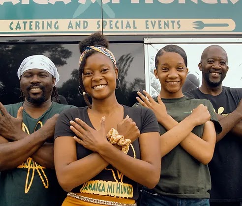 Four Black workers standing with arms crossed smiling